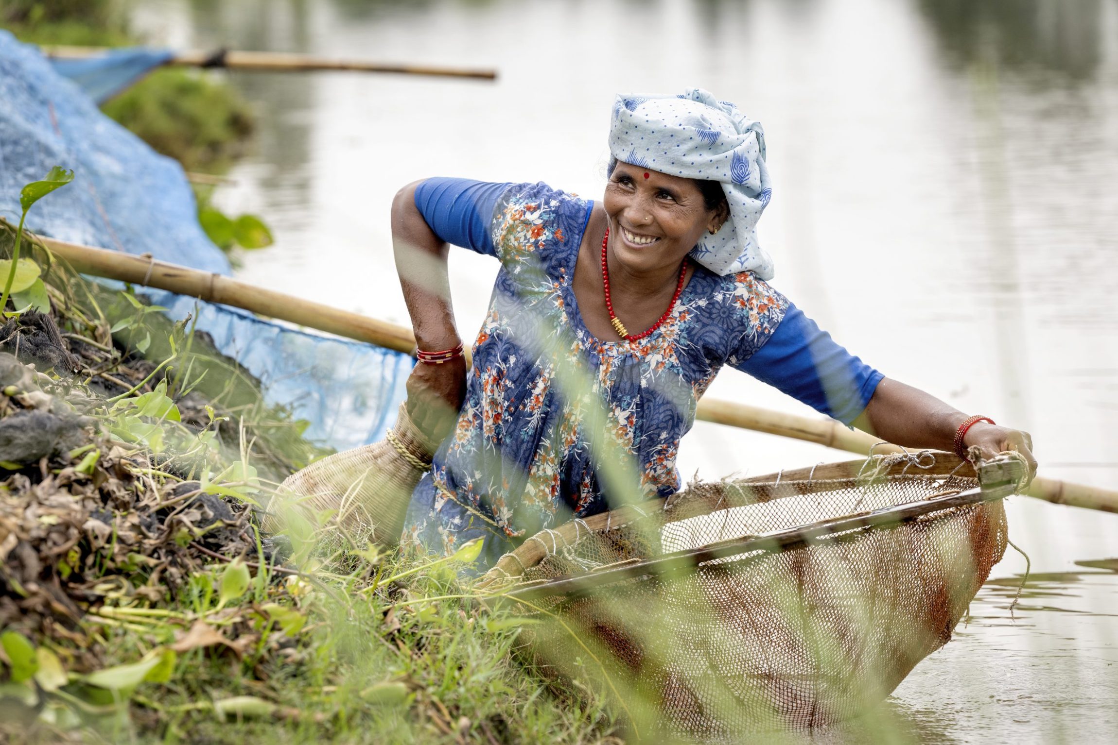 Smilende kvinde i kjole st&aring;r med fiskenet