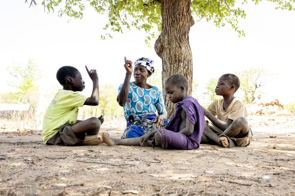 Fatima sitting in the ground with children in Malawi