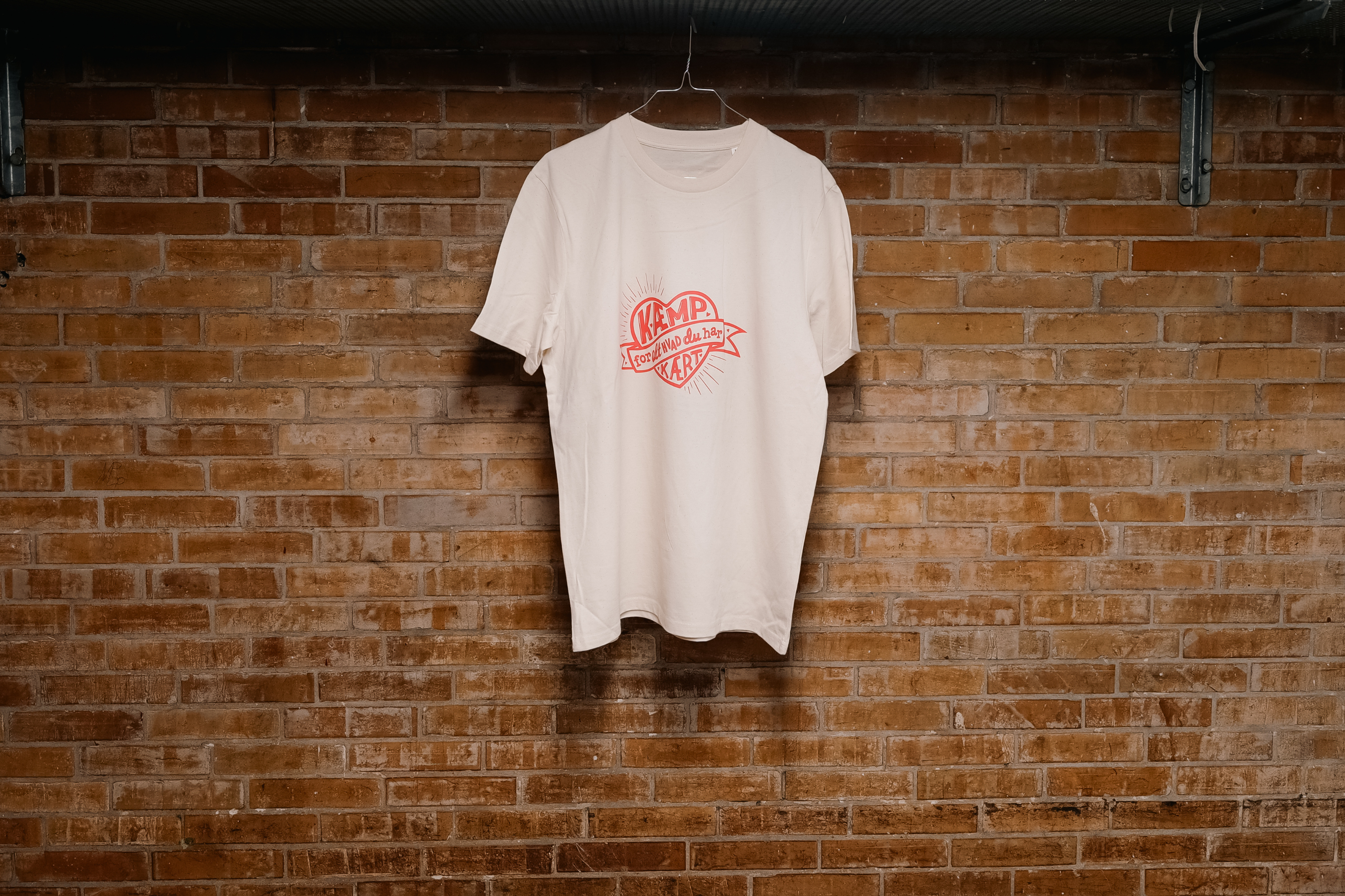 Kritisk Pynt X Folkekirkens N&oslash;dhj&aelig;lp - T-shirt med budskabet 'K&aelig;mp for alt, hvad du har k&aelig;rt'.