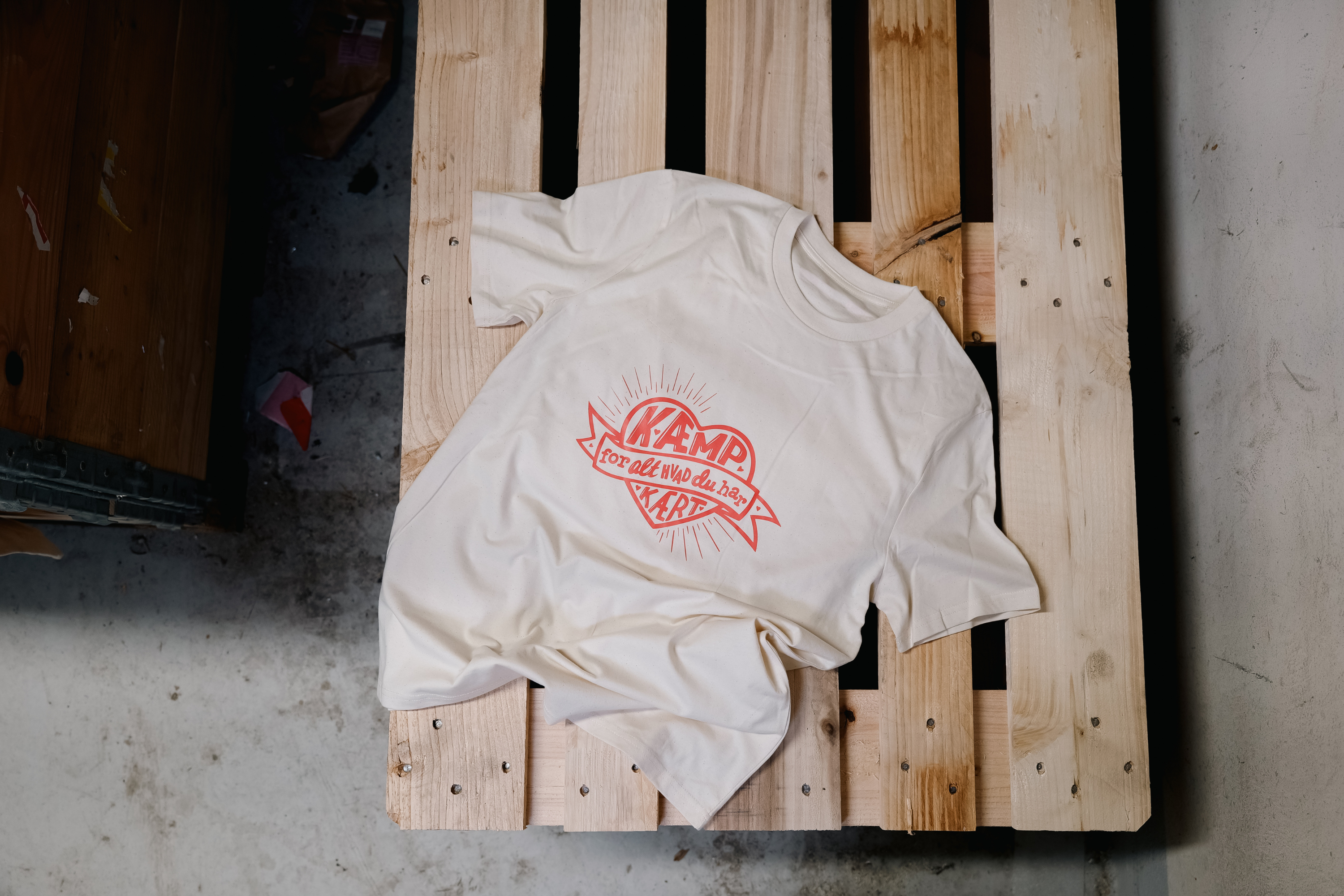 Kritisk Pynt X Folkekirkens N&oslash;dhj&aelig;lp-tshirt ligger p&aring; palle.