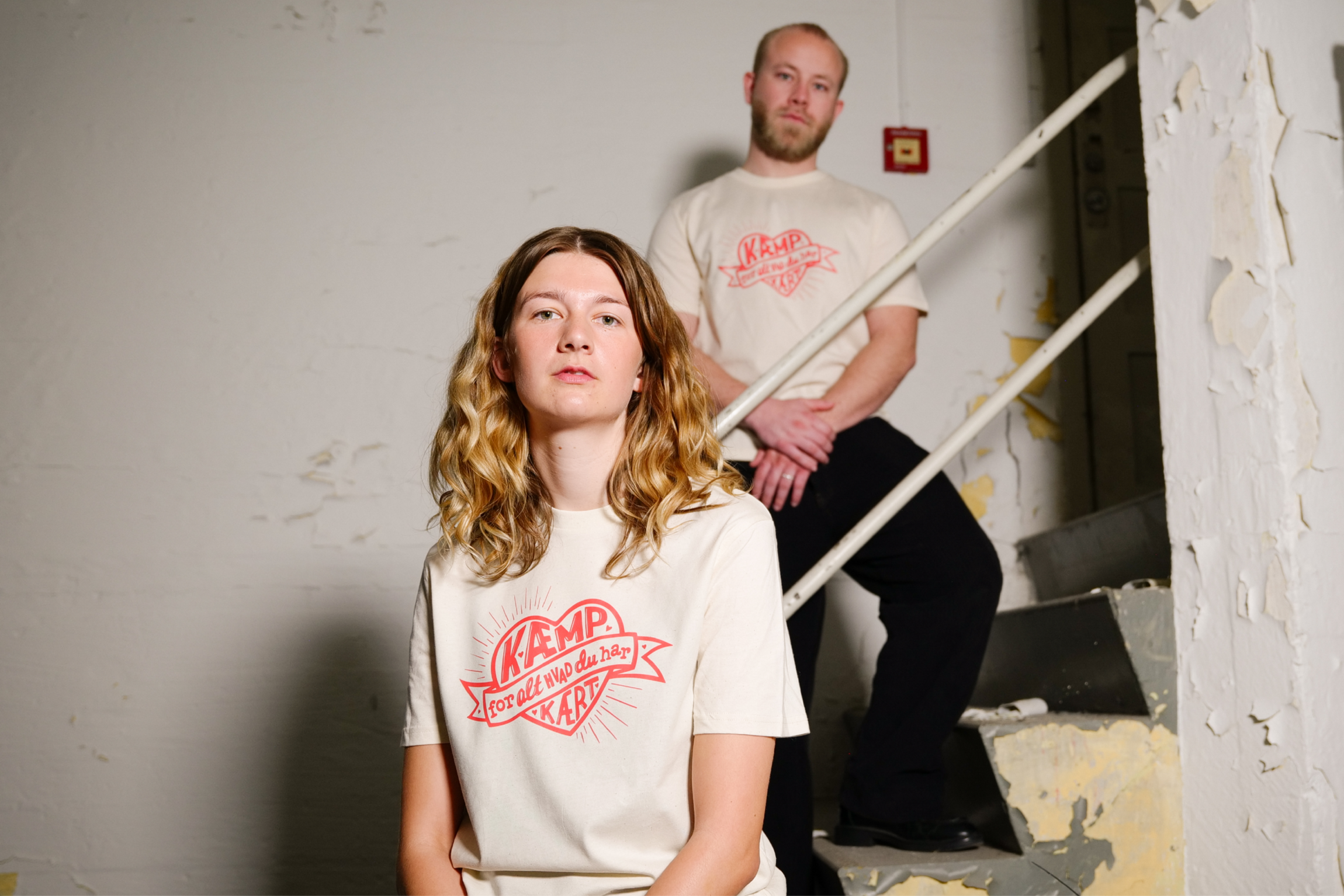 To modeller bærer Kritisk Pynt X Folkekirkens Nøhjdælp t-shirt med budskabet 'Kæmp for alt, hvad du kært', der sælges i Folkekirkens Nødhjælp webshop.